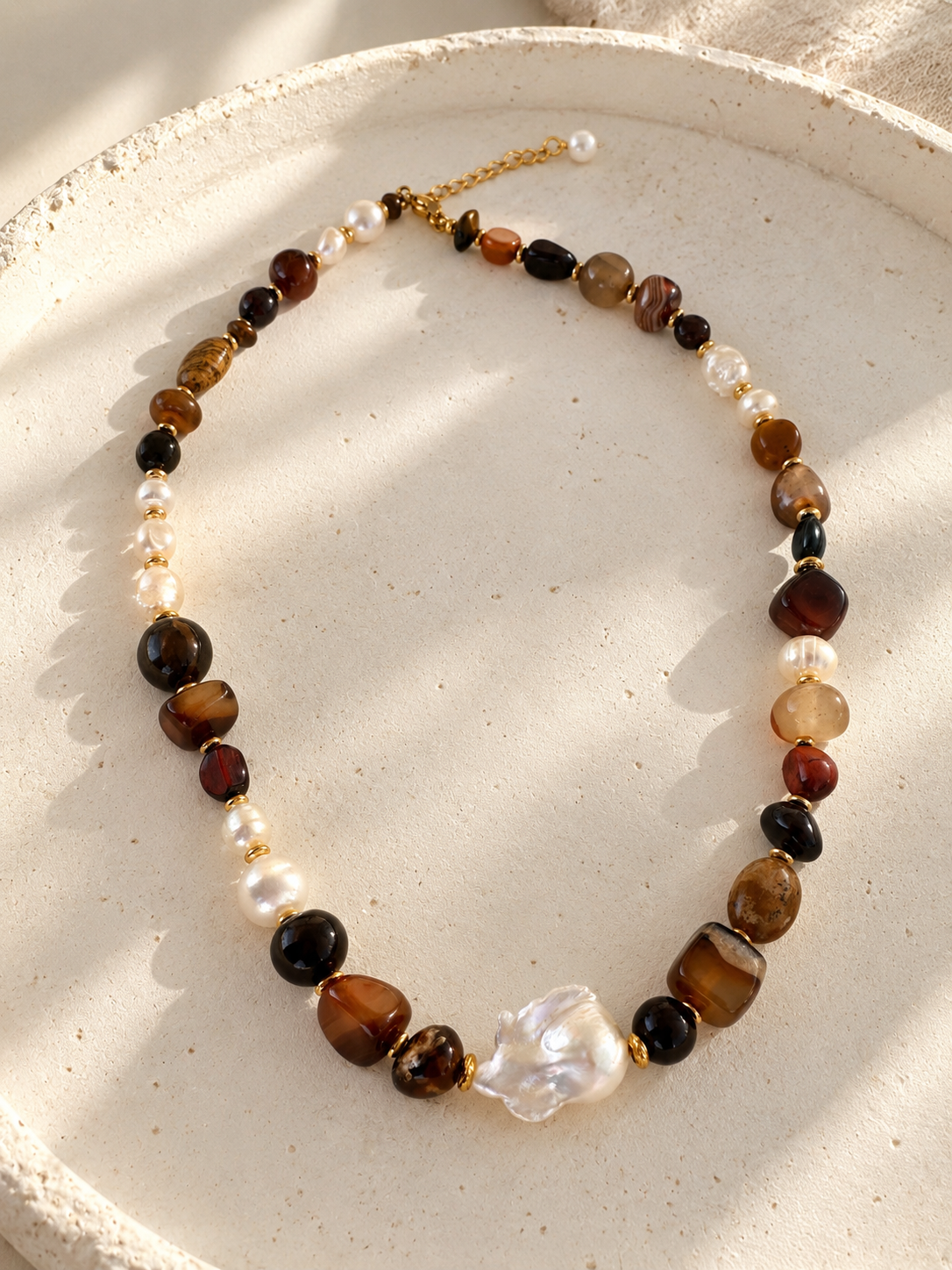 תקריב של שרשרת אבני חן ופנינה טבעית AMBER COAST